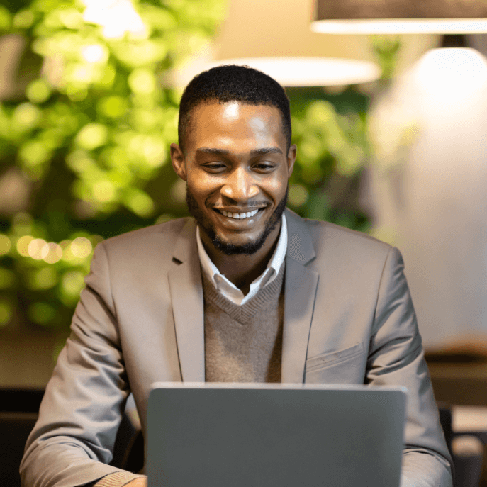 Man smiling whilst reading on his laptop