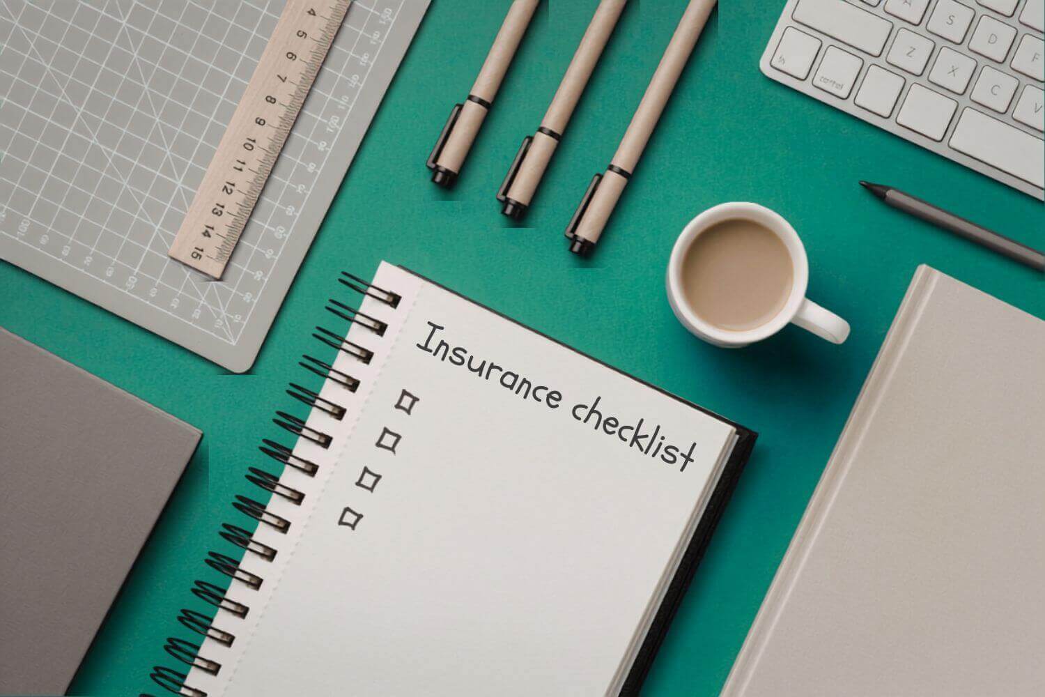 A flat lay of a desk with stationery and notebook with writing 'insurance checklist', representing guide on questions to ask when buying contractor insurance